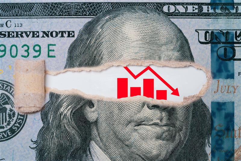 100 dollar bill ripped with a declining bar graph