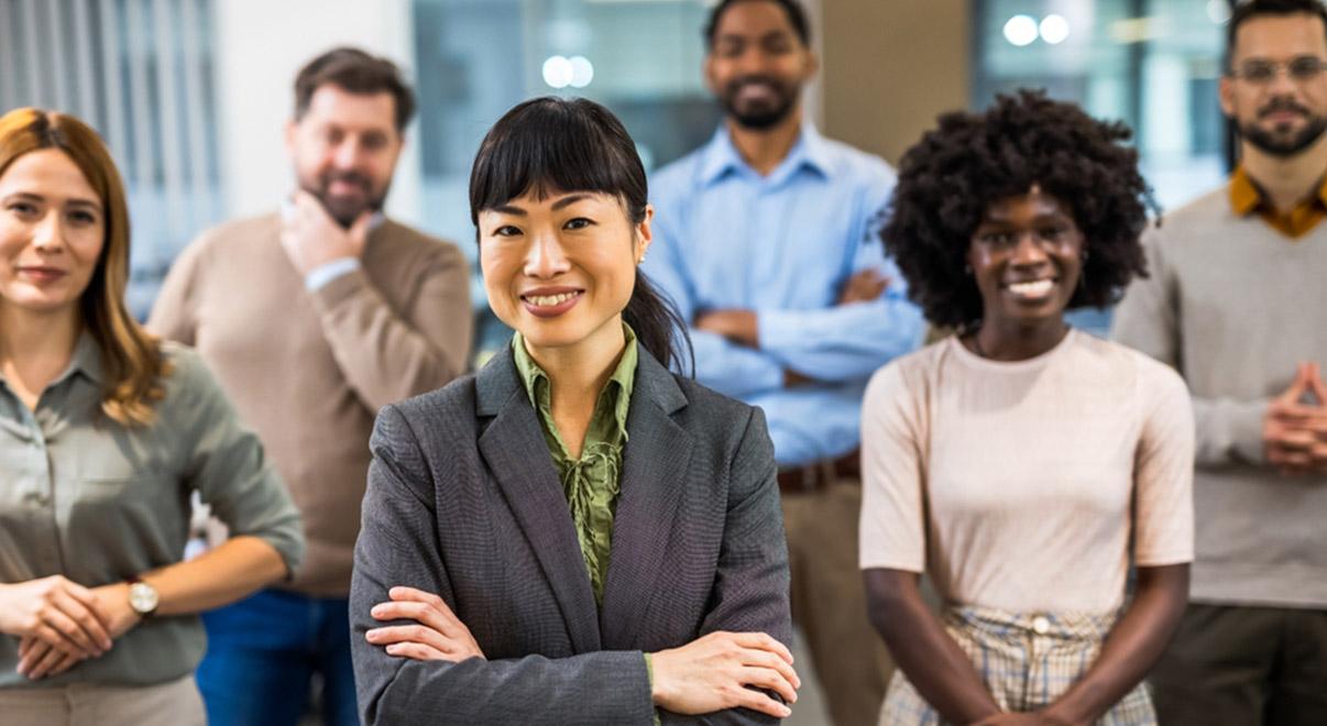 Diverse group of professionals standing together, smiling confidently in an office.