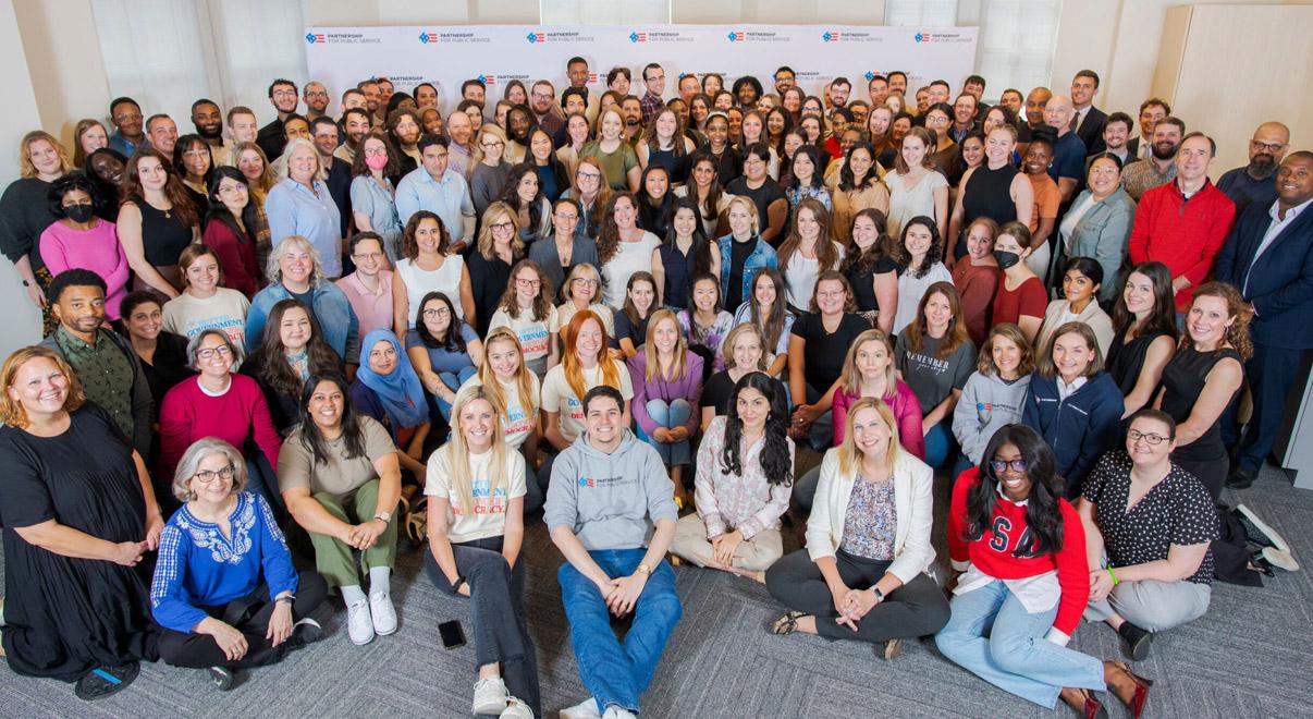 Large group photo of diverse employees gathered in an office.