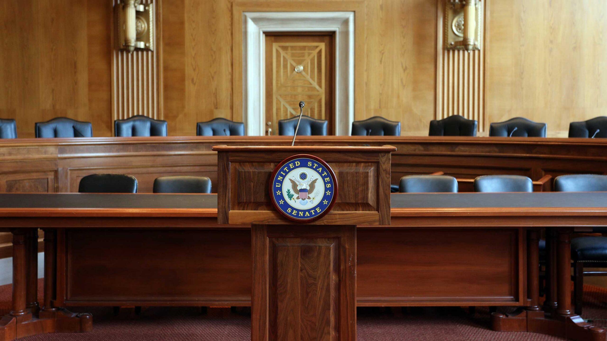 Black chairs behind a long wooden desk