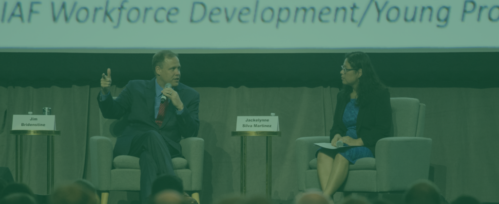 Teal filtered image of two people talking on stage