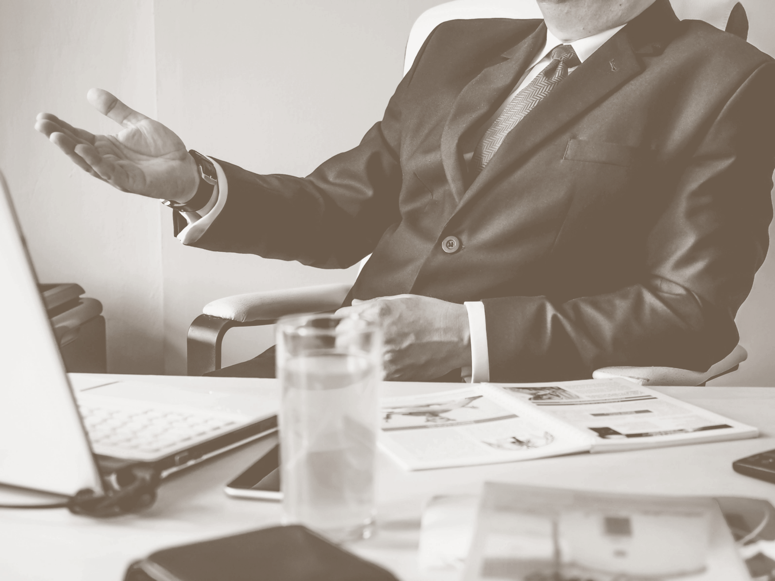 Sepia toned image of a man in suit working on a laptop
